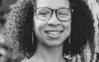 Smiling woman with curly hair outdoors.