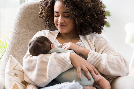 Birthing parent is breastfeeding her newborn child