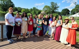 Group of women holding books by a lake.