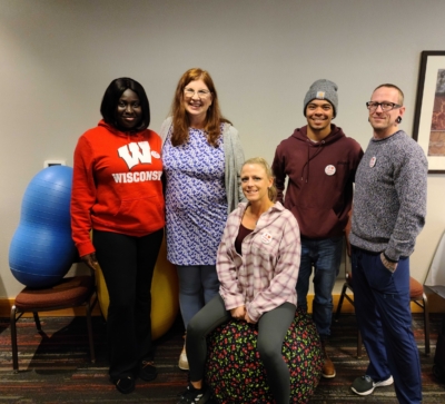 Group of five people posing together indoors.